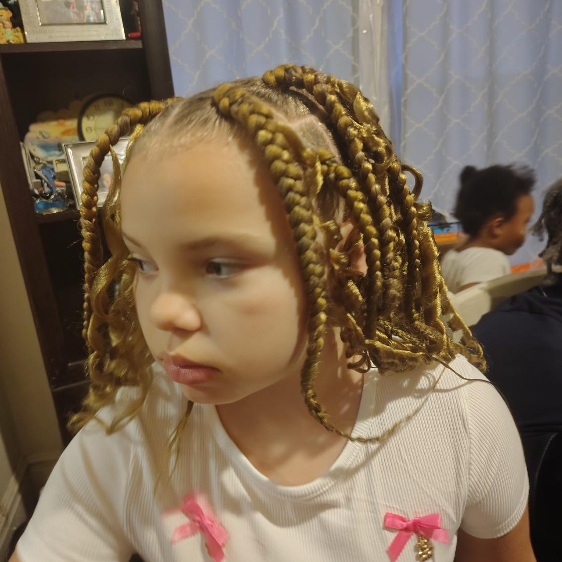 Braided hair finished with two pink bows, styled by Jazmiane